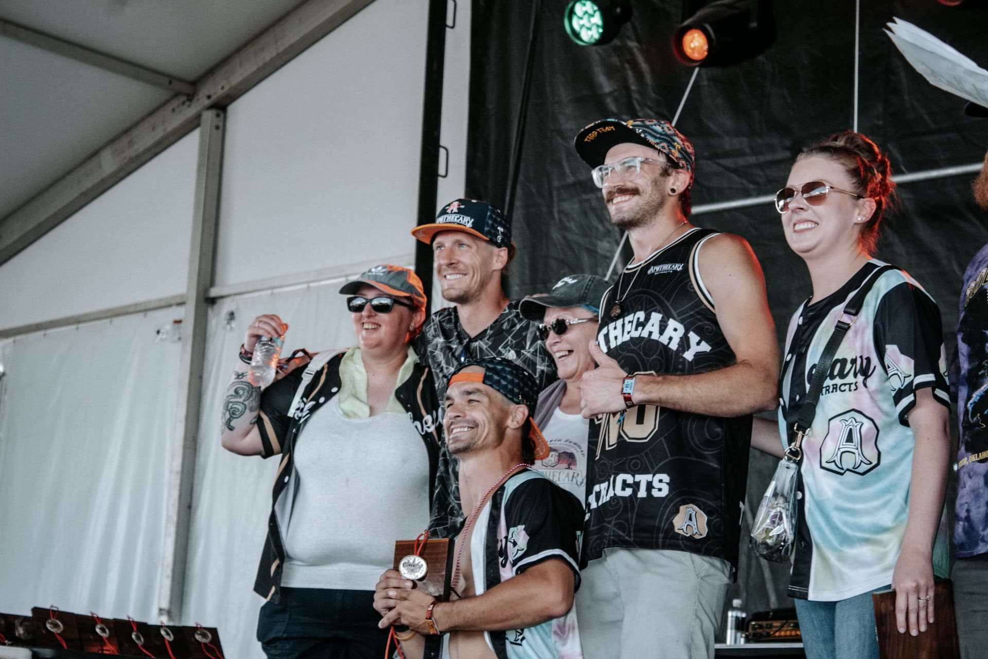 Apothecary team celebrating an award on stage in Apothecary Extracts jerseys